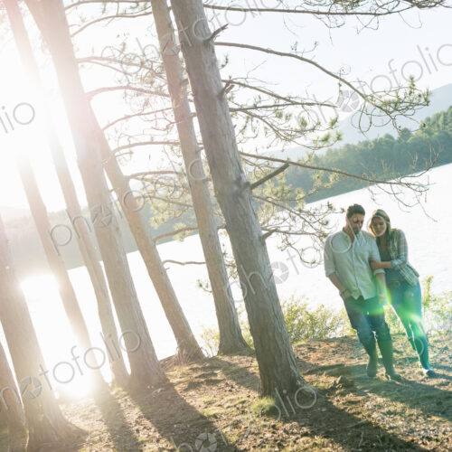 A couple walking in woodland on the shores of a lake. A couple walking in woodland on the shores of a lake.