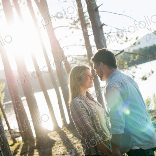 A couple walking in woodland on the shores of a lake. A couple walking in woodland on the shores of a lake.