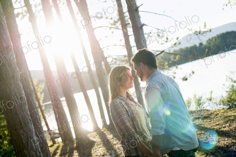 A couple walking in woodland on the shores of a lake.