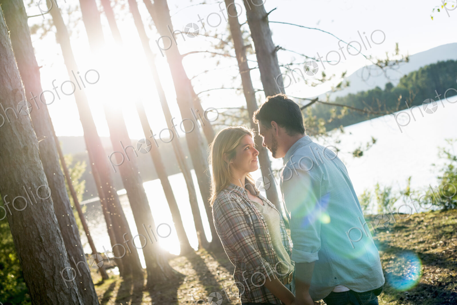 A couple walking in woodland on the shores of a lake.