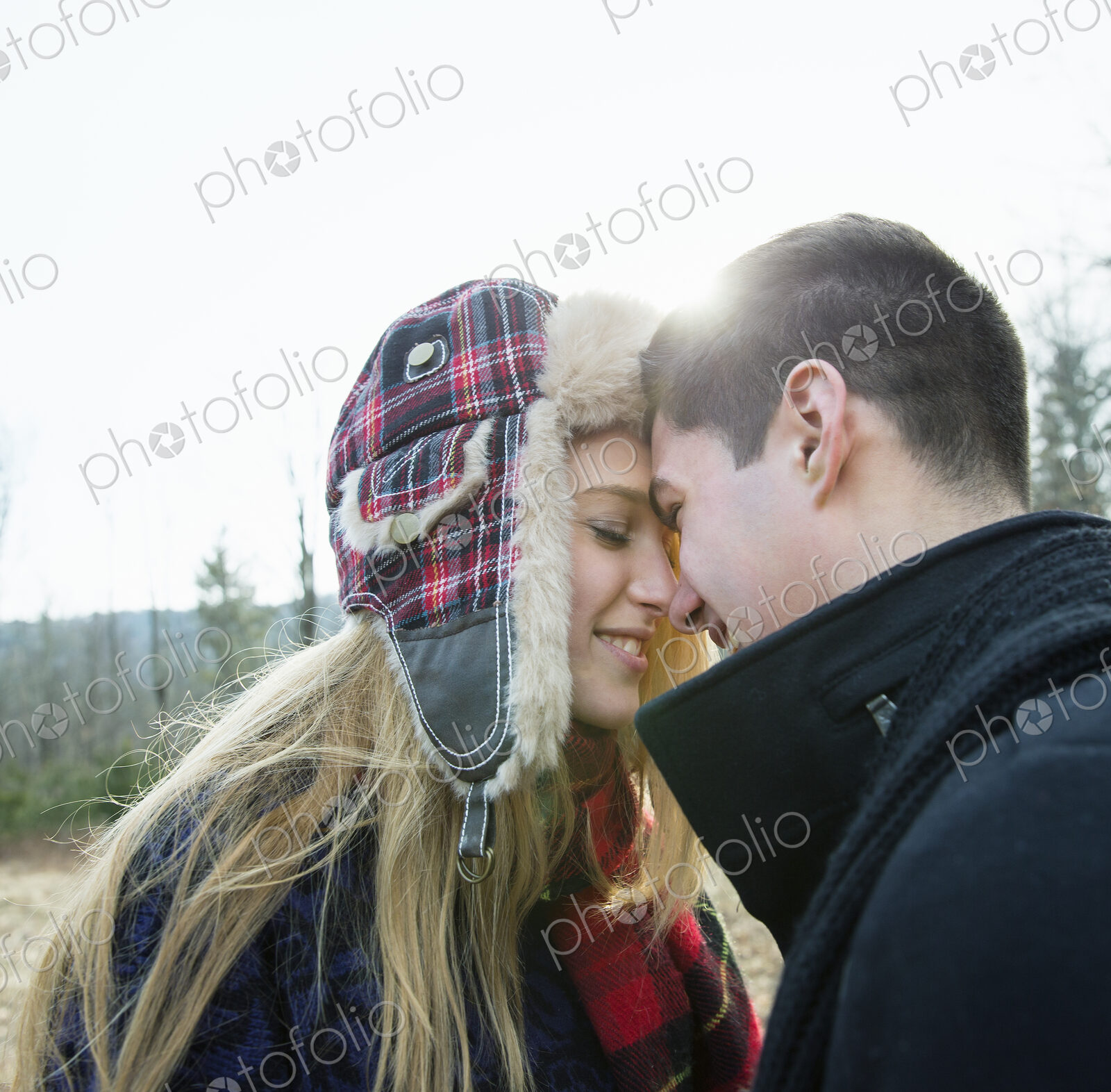 A couple, young man and woman, face to face embracing, outdoors on a cold winter day.