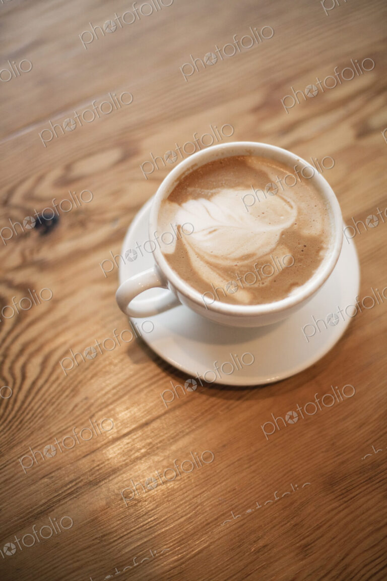 A cup of frothy coffee in a white china cup with a saucer. Cappuchino.