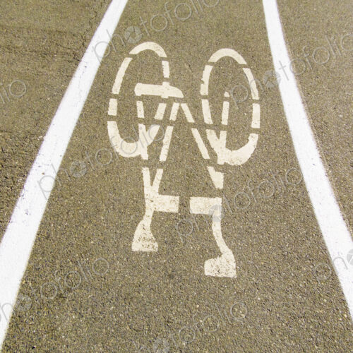 A cycle route in a public park, white painted outline of a bicycle, cycling lane on a…