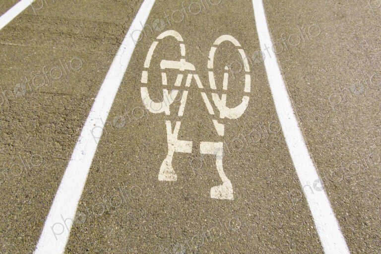 A cycle route in a public park, white painted outline of a bicycle, cycling lane on a…