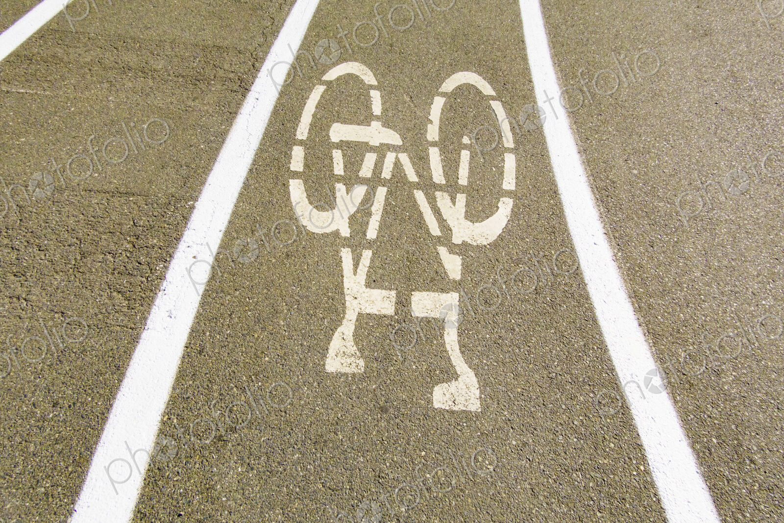 A cycle route in a public park, white painted outline of a bicycle, cycling lane on a…
