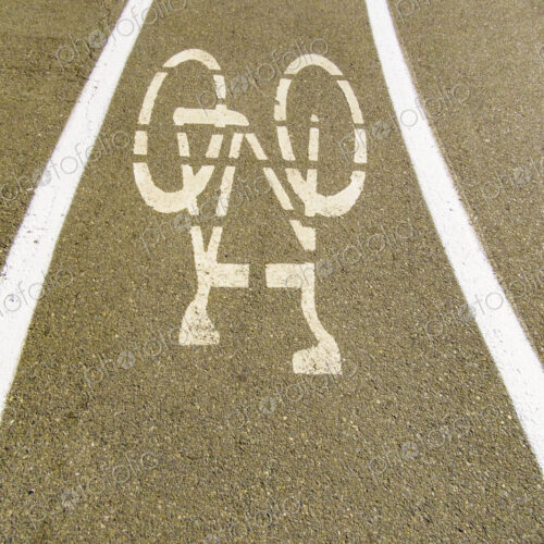 A cycle route in a public park, white painted outline of a bicycle, cycling lane on a…
