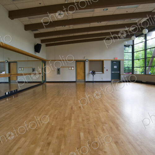 A dance ballet studio,with a sprung wooden floor, barre and wall mirrors.