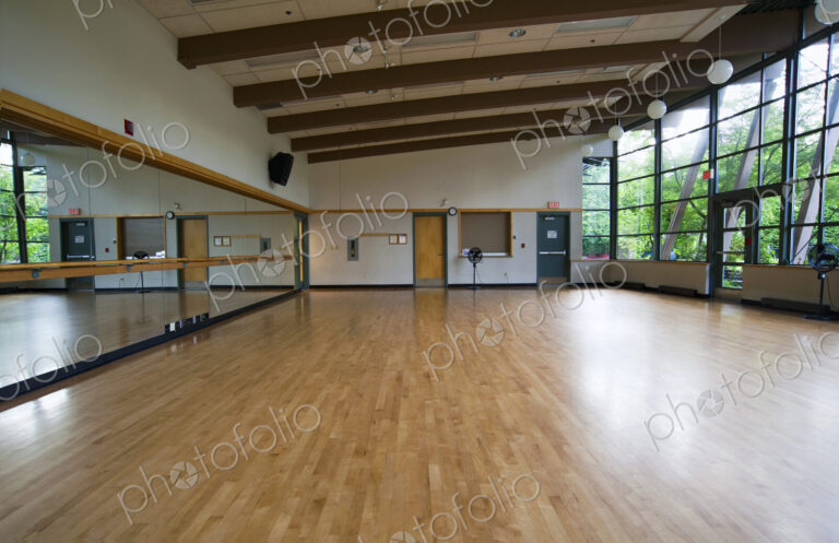 A dance ballet studio,with a sprung wooden floor, barre and wall mirrors.