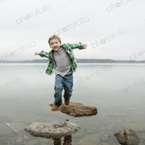 A day out at Ashokan lake. A boy jumping across stepping stones.