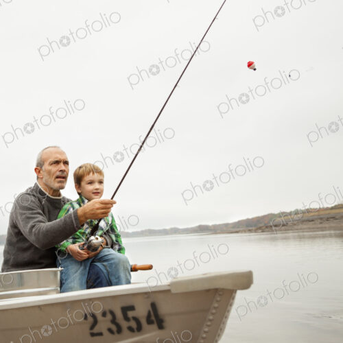 A day out at Ashokan lake. A man showing a young boy how to fish, sitting in a boat.