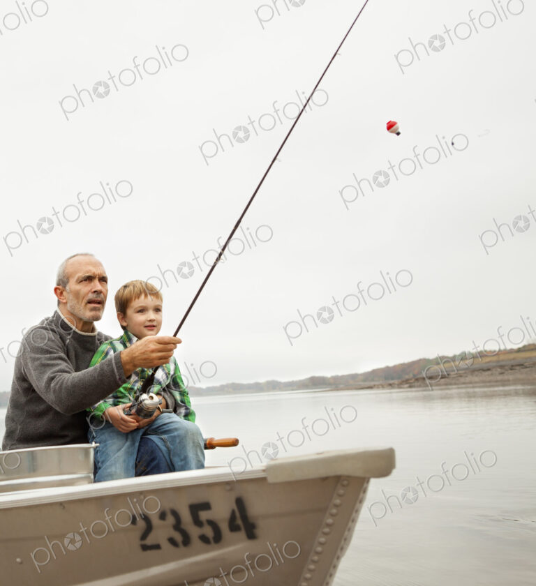 A day out at Ashokan lake. A man showing a young boy how to fish, sitting in a boat.