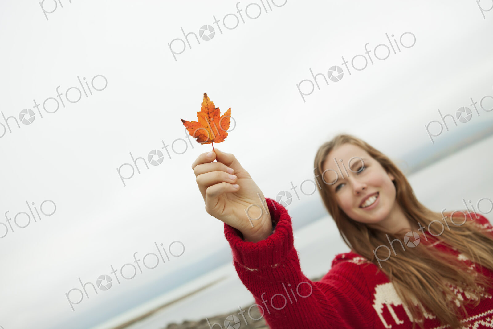 A day out at Ashokan lake. A young girl in a red winter knitted jumper holding up a…
