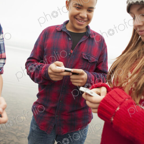 A day out at Ashokan lake. Teenagers, a girl and two boys texting and looking at their… A day out at Ashokan lake. Teenagers, a girl and two boys texting and looking at their…