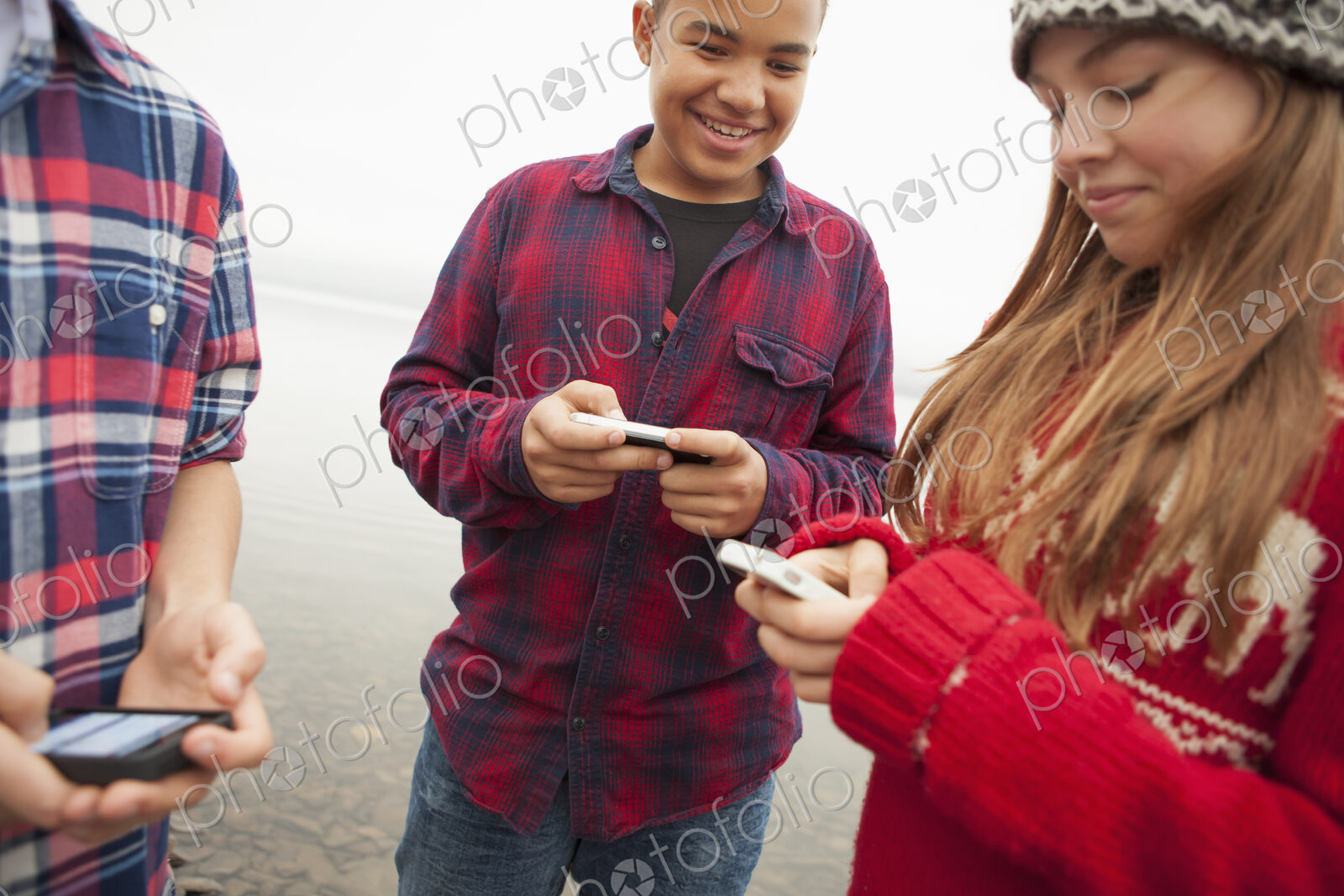 A day out at Ashokan lake. Teenagers, a girl and two boys texting and looking at their…