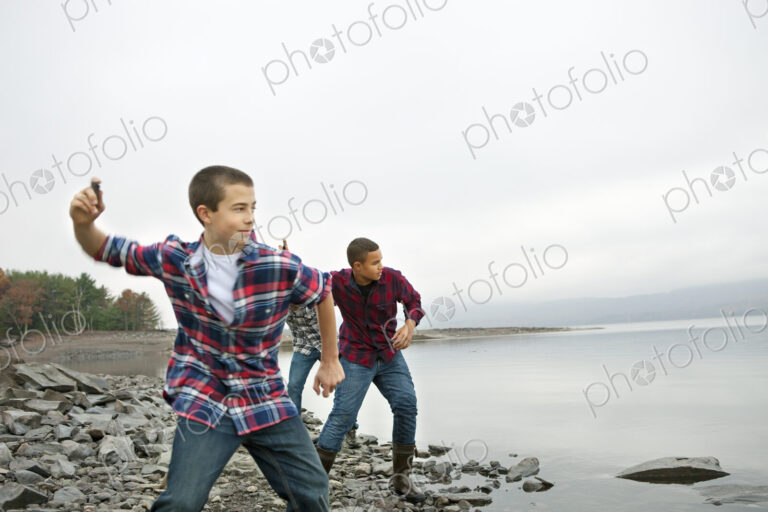 A day out at Ashokan lake. Three boys on the shore throwing skimmers pebbles across…