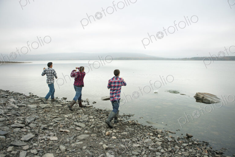 A day out at Ashokan lake. Three boys on the shore throwing skimmers pebbles across…