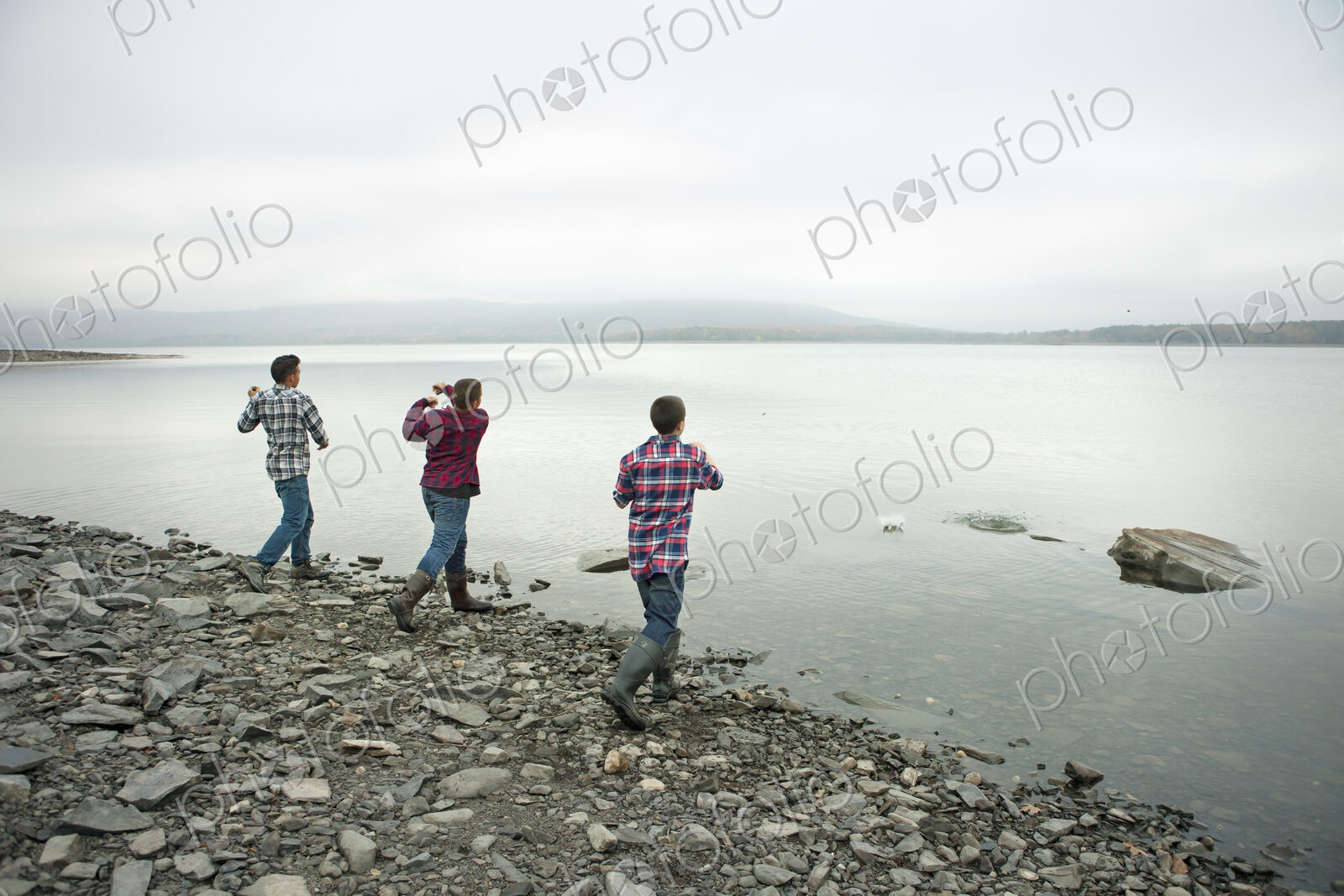 A day out at Ashokan lake. Three boys on the shore throwing skimmers pebbles across…