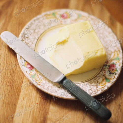 A decorated plate and a half used block of butter. Knife. A decorated plate and a half used block of butter. Knife.