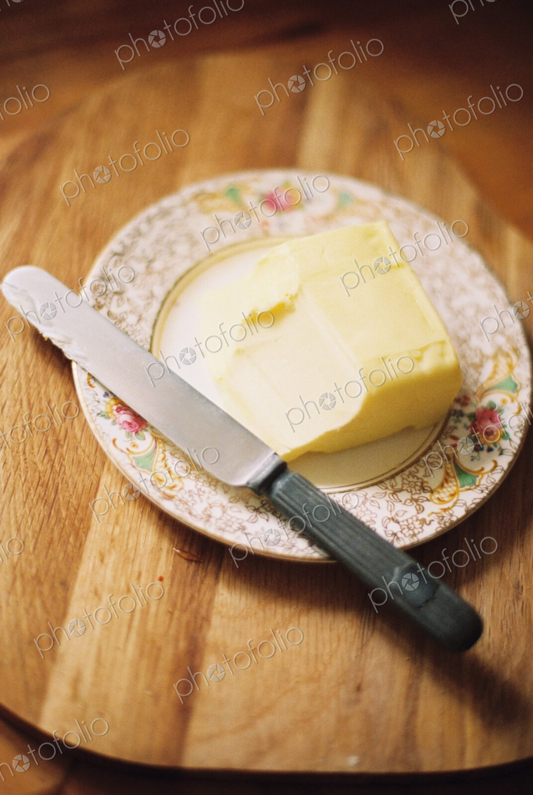 A decorated plate and a half used block of butter. Knife.