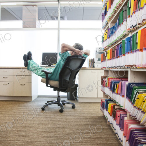 A dentist taking a break with his feet up on a file cabinet.