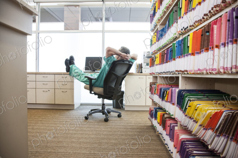 A dentist taking a break with his feet up on a file cabinet.