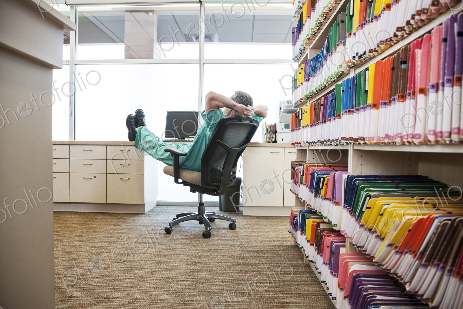 A dentist taking a break with his feet up on a file cabinet.