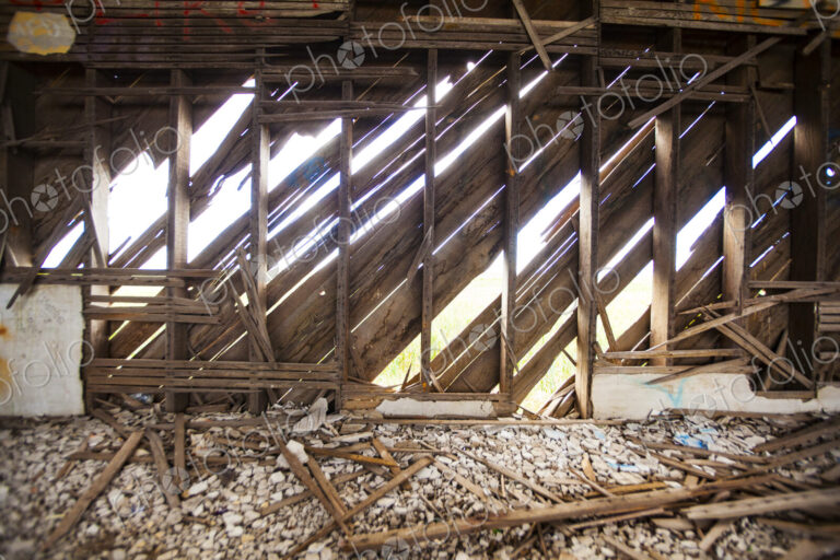 A derelict house, abandoned property, rotten broken beams and joists, sunlight coming…