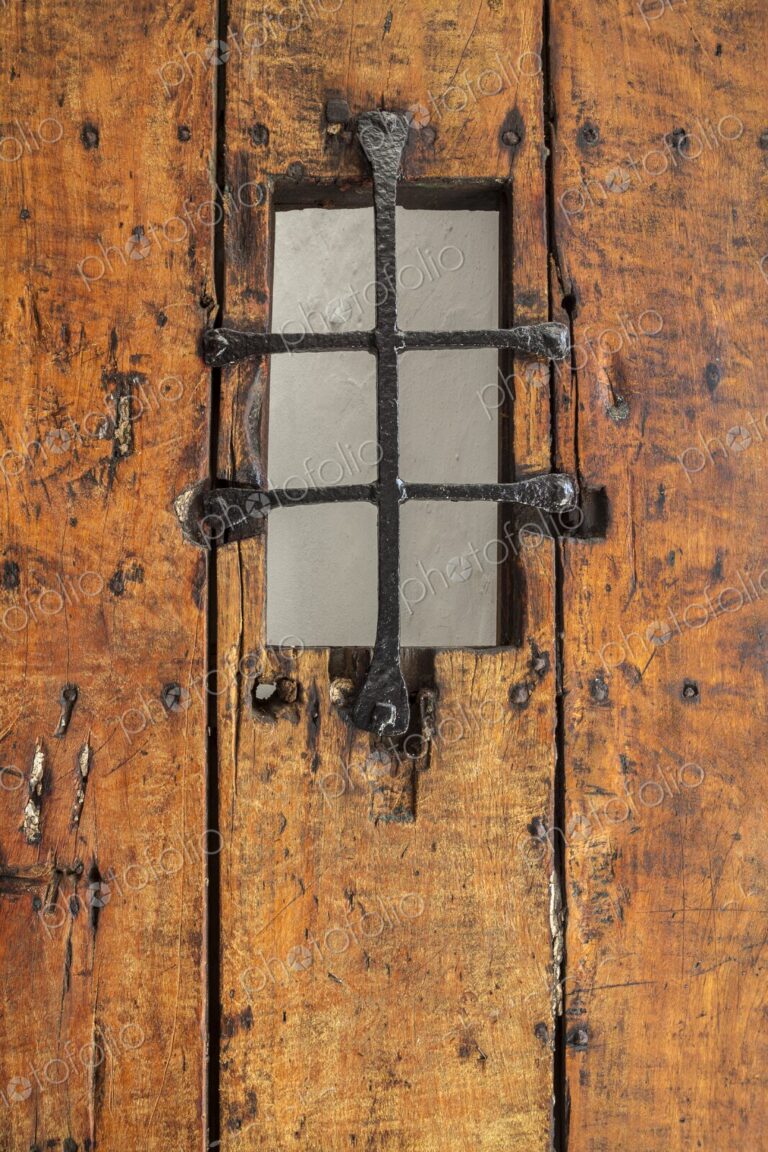 A detailed view of an old wooden door with an iron grate window at Castillo San Felipe…