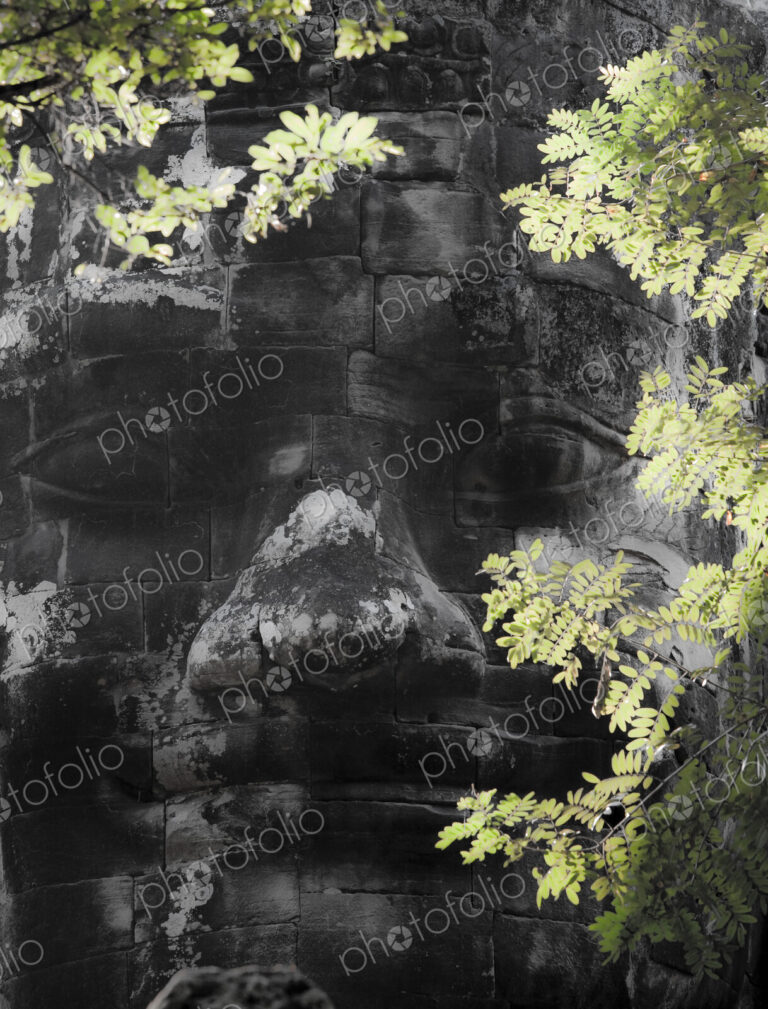 A diety head, a god's face in stone blocks, on the wall at Angkor Thom, part of the…