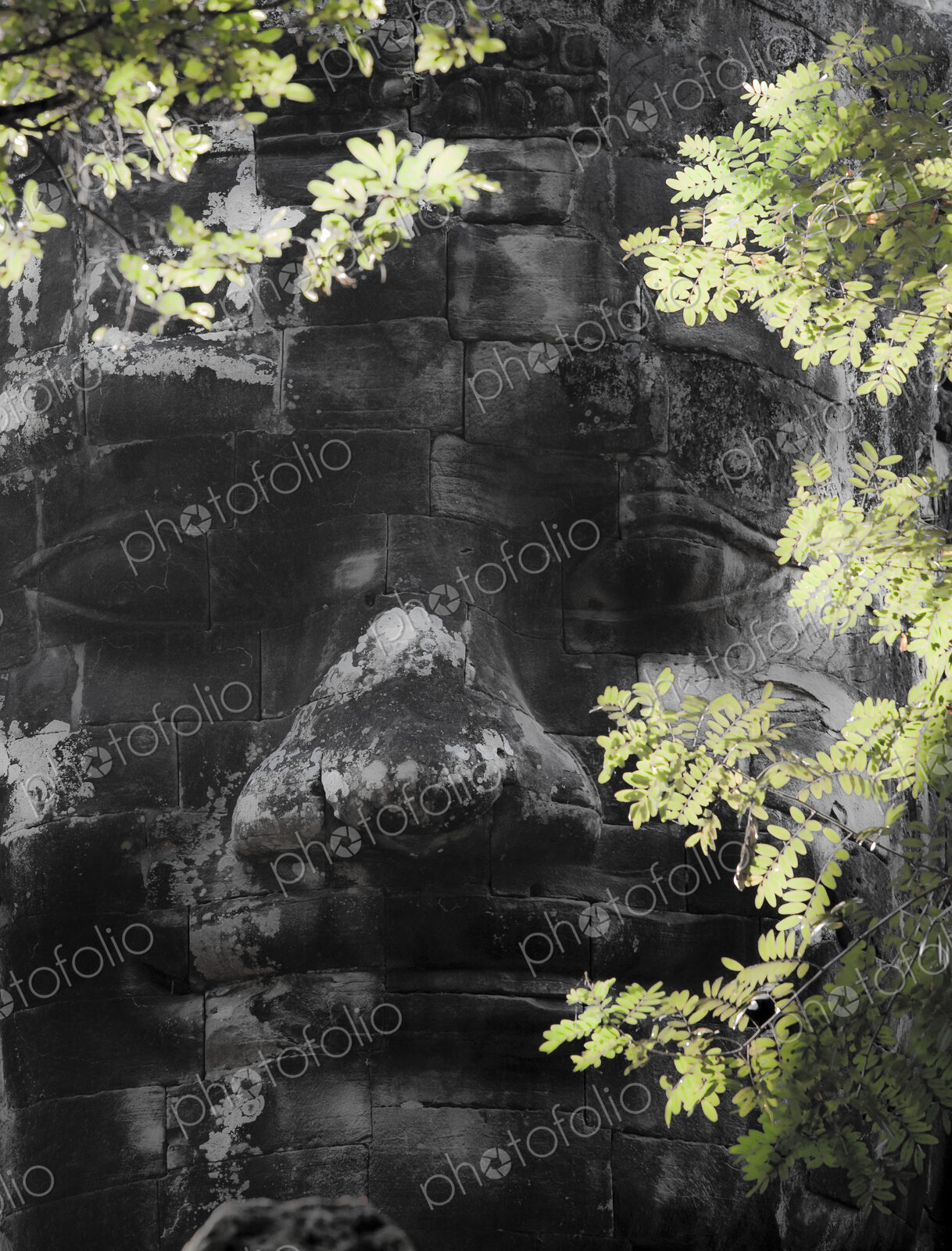 A diety head, a god’s face in stone blocks, on the wall at Angkor Thom, part of the…