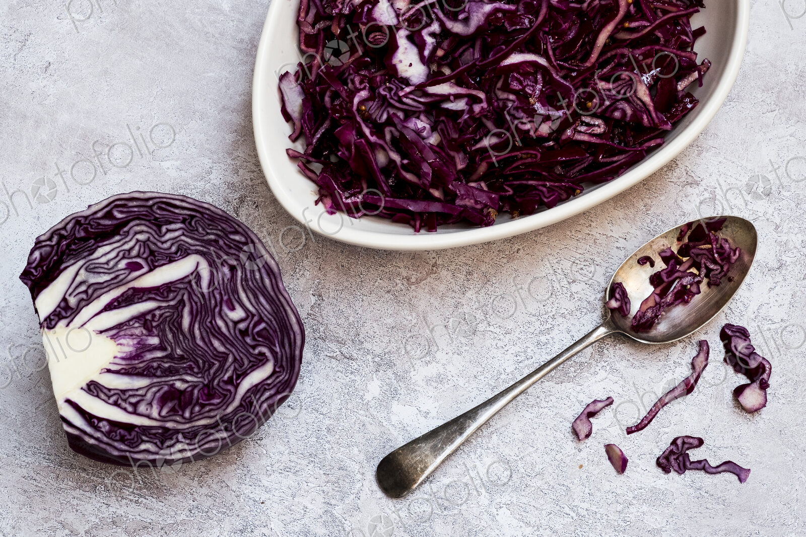 A dish of cooked red cabbage and half a raw cabbage.