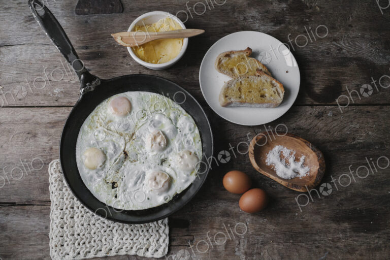 A dish of eggs, bread and sauce laid out on a table.