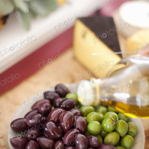 A dish of fresh organic vegetables. Green and black olives on a plate with a drizzling…