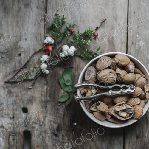 A dish of nuts and a nut cracker on a table with a sprig of yew wit red berries. A dish of nuts and a nut cracker on a table with a sprig of yew wit red berries.
