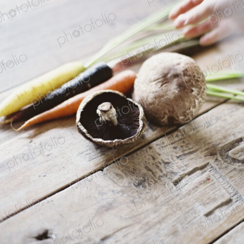 A domestic kitchen table with a worn scrubbed surface. A bunch of carrots, and… A domestic kitchen table with a worn scrubbed surface. A bunch of carrots, and…
