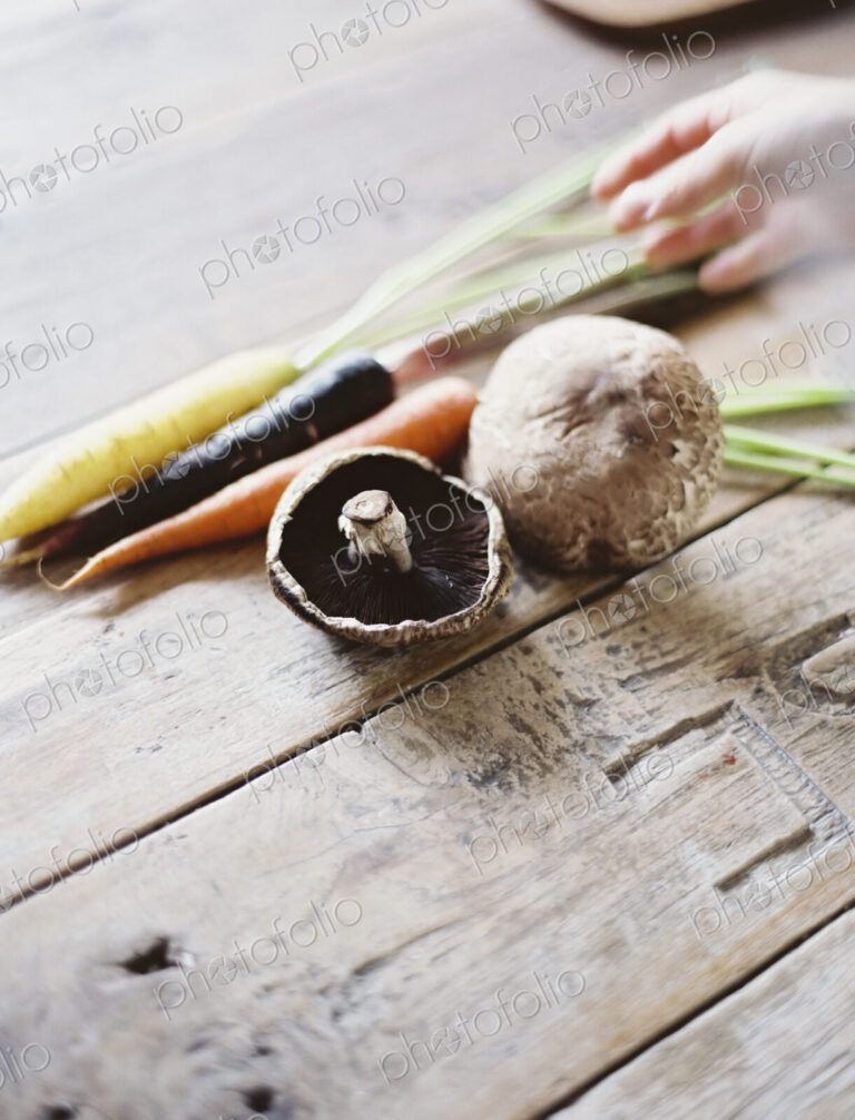 A domestic kitchen table with a worn scrubbed surface. A bunch of carrots, and…
