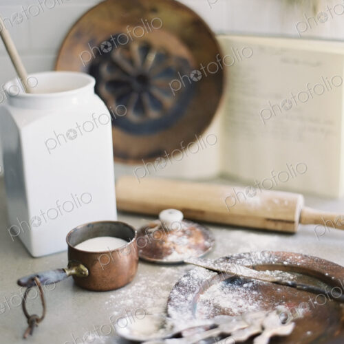 A domestic kitchen table. A large group of kitchen utensils, spoons, a pan and a… A domestic kitchen table. A large group of kitchen utensils, spoons, a pan and a…