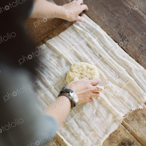 A domestic kitchen table. A view from above of a woman wrapping fresh pastry in a… A domestic kitchen table. A view from above of a woman wrapping fresh pastry in a…