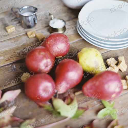A domestic kitchen tabletop. A small group of fresh organic pears and a stack of white… A domestic kitchen tabletop. A small group of fresh organic pears and a stack of white…