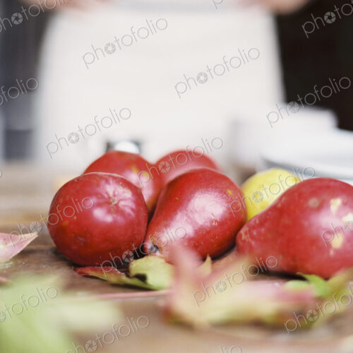 A domestic kitchen tabletop. A small group of fresh organic pears and a stack of white… A domestic kitchen tabletop. A small group of fresh organic pears and a stack of white…