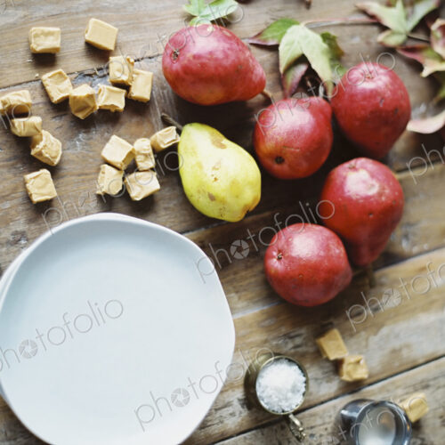 A domestic kitchen tabletop. A small group of fresh organic pears and a stack of white… A domestic kitchen tabletop. A small group of fresh organic pears and a stack of white…