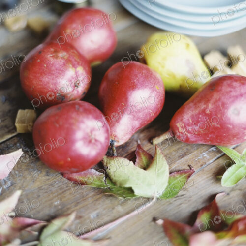 A domestic kitchen tabletop. A small group of fresh organic pears and a stack of white… A domestic kitchen tabletop. A small group of fresh organic pears and a stack of white…