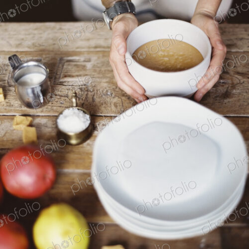 A domestic kitchen tabletop. A stack of white plates and fresh pears and a stack of… A domestic kitchen tabletop. A stack of white plates and fresh pears and a stack of…