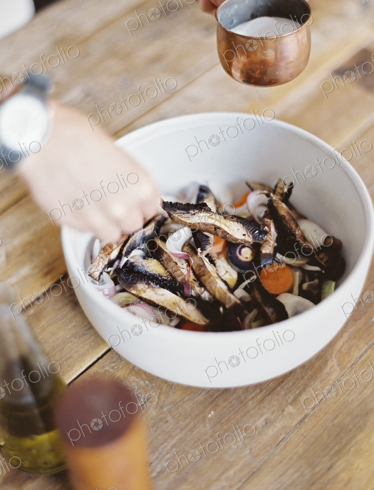 A domestic kitchen. A bowl of fresh chopped vegetables, in a white bowl. A person’s…