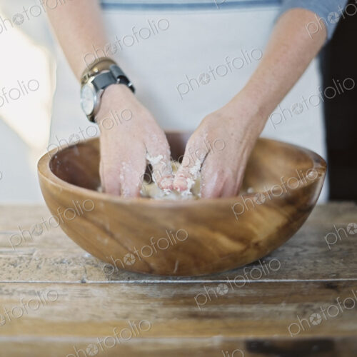 A domestic kitchen. A cook preparing pastry, mixing it by hand on a tabletop. A domestic kitchen. A cook preparing pastry, mixing it by hand on a tabletop.