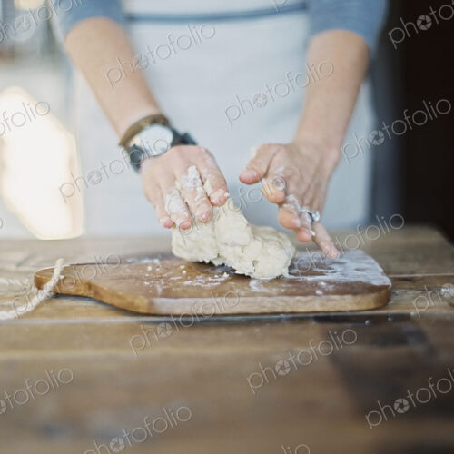 A domestic kitchen. A cook preparing pastry, mixing it by hand on a tabletop. A domestic kitchen. A cook preparing pastry, mixing it by hand on a tabletop.