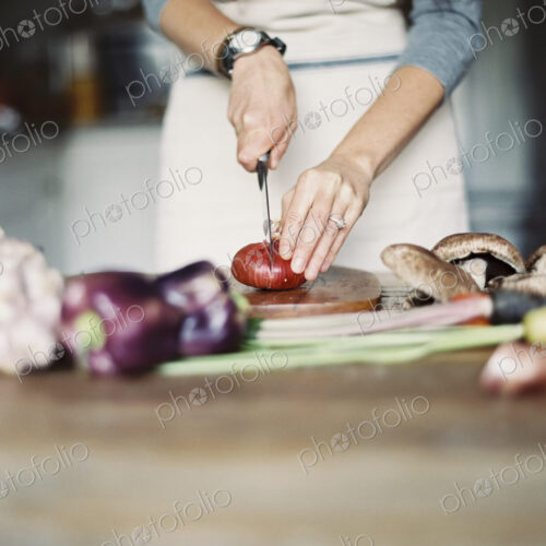 A domestic kitchen. A table top. Young woman chopping fresh vegetables with a knife. A domestic kitchen. A table top. Young woman chopping fresh vegetables with a knife.