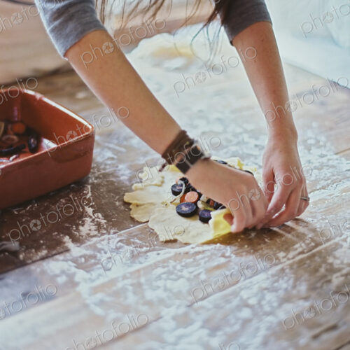 A domestic kitchen. A woman creating an open pastry tart with vegetables. A domestic kitchen. A woman creating an open pastry tart with vegetables.