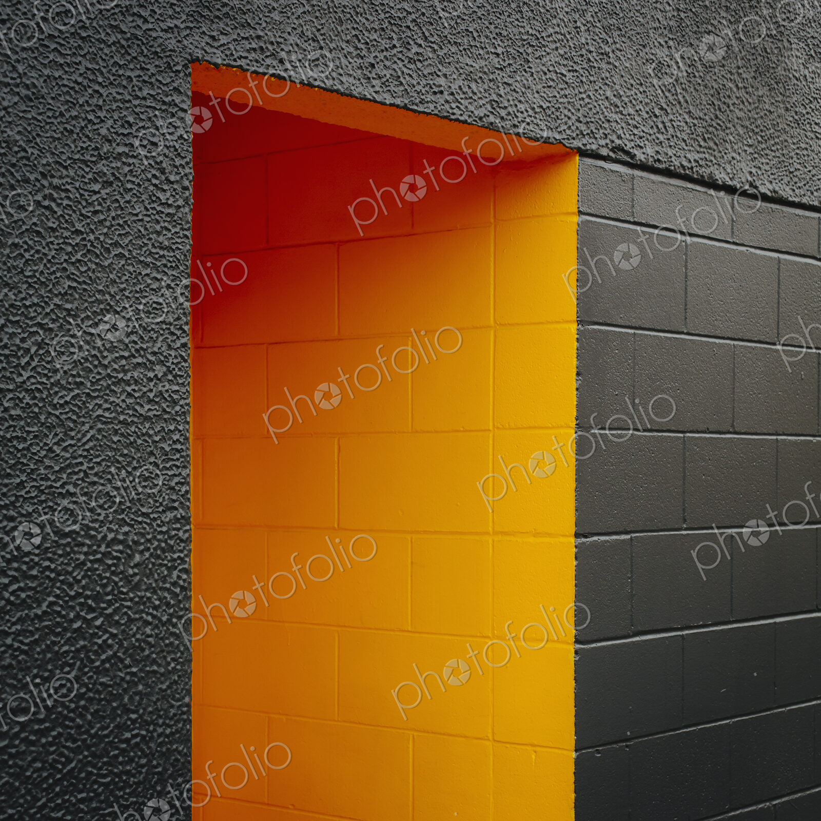 A doorway recess, painted orange in a grey block concrete wall.