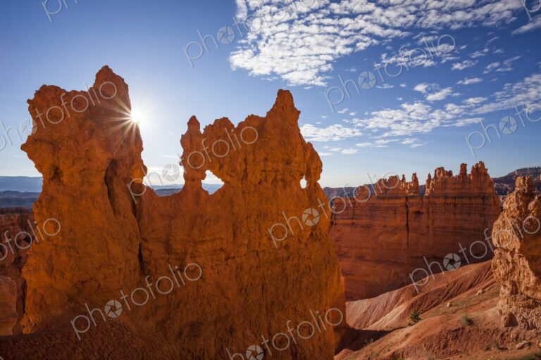A dramatic hoodoo wall pierced with natural windows catches the sunburst at sunrise in…